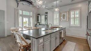 Een ruime keuken met een groot eiland, witte kasten en een decoratieve vis aan de muur.