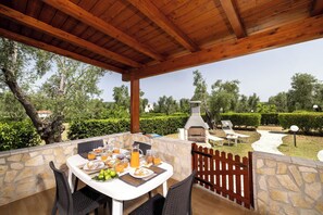 An outdoor patio with a stone wall, wooden ceiling, and a stone table set for breakfast. - Detached  Villa, 55 square meters, on the ground floor with private garden of 150 square meters with barbecue and sunbeds (Vieste)