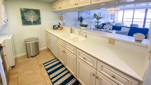 Una cocina moderna con armarios blancos, un ventanal y vistas al exterior.