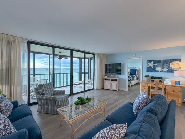 A spacious living room with a balcony, a television, and a dining area.