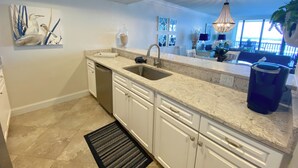 A modern kitchen with white cabinetry, a marble countertop, and a built-in dishwasher. - Sanibel Harbour Resort Harbour Tower 616      Updated luxury condo with stunning views (Fort Myers)