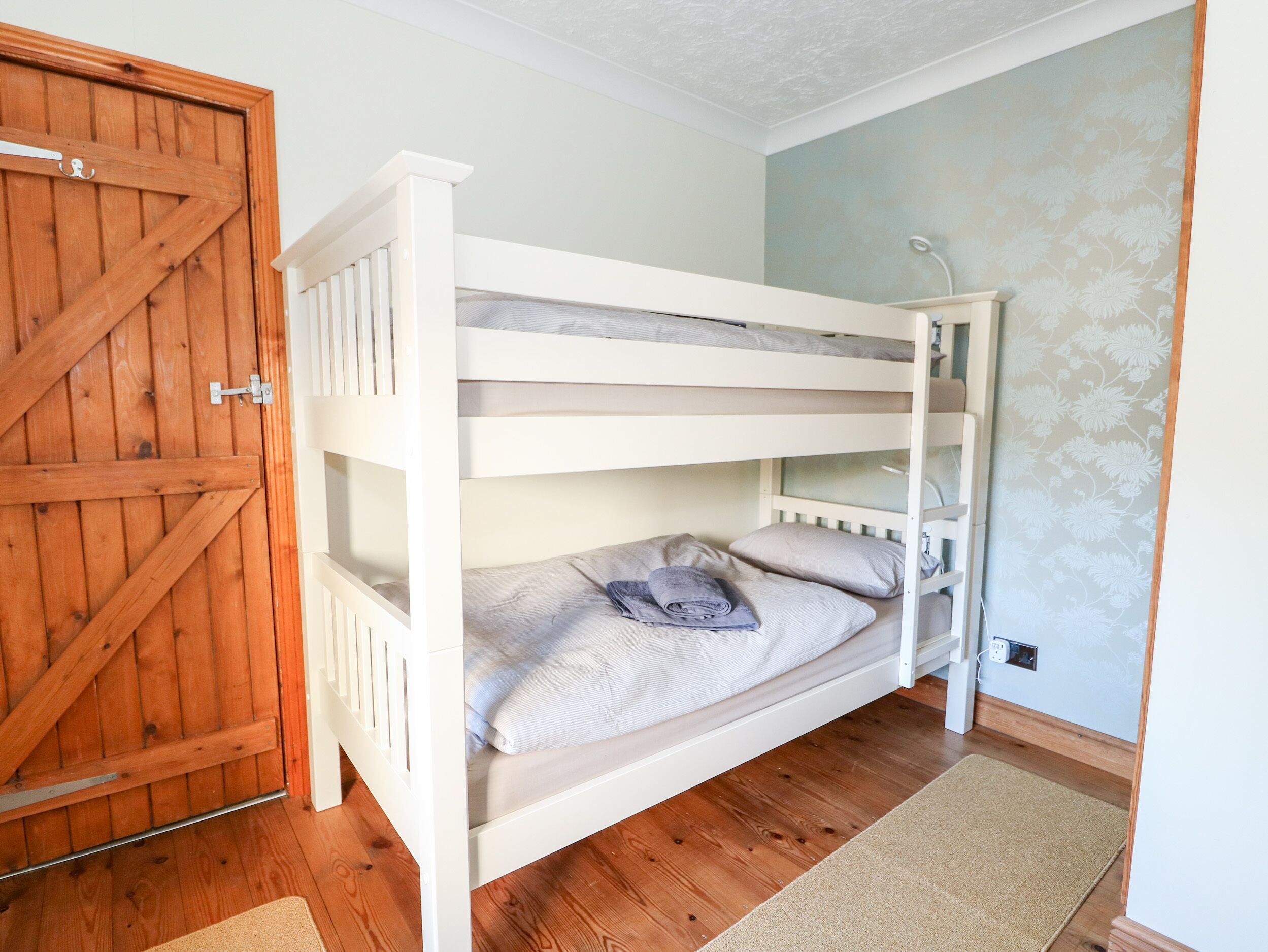 Une chambre avec un lit superposé, une porte en bois et un mur bleu clair.