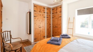 Ein Schlafzimmer mit Bett, Holzschrank, Stuhl und Fenster mit Aussicht.