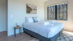 Camera da letto moderna con un letto grande, un tavolino, un quadro appeso e una finestra con persiane.