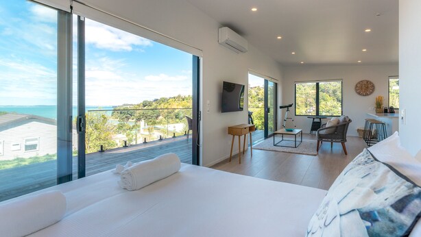 Una camera da letto moderna con un letto grande, vista sul mare e un balcone con zona pranzo.
