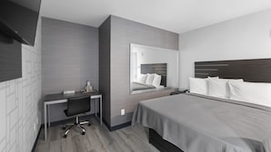 A modern hotel room with a large bed, a desk, and a mirror. - Hotel 365 Bronx (Bronx)