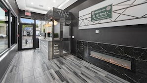 A hotel lobby with a reception desk, a welcome sign, a fireplace, and a sign indicating the exit. - Hotel 365 Bronx (Bronx)