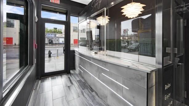 A modern interior with a reception desk, glass doors, and a view of the outside. - Hotel 365 Bronx (Bronx)