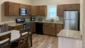 A kitchen with wooden cabinets, a stainless steel refrigerator, a microwave, a stove, and a dishwasher.