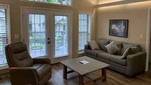 A living room with a sofa, a chair, a coffee table, and a painting on the wall.