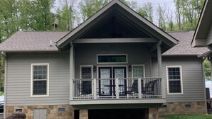 A two-story house with a covered porch, stone foundation, and a stone chimney.