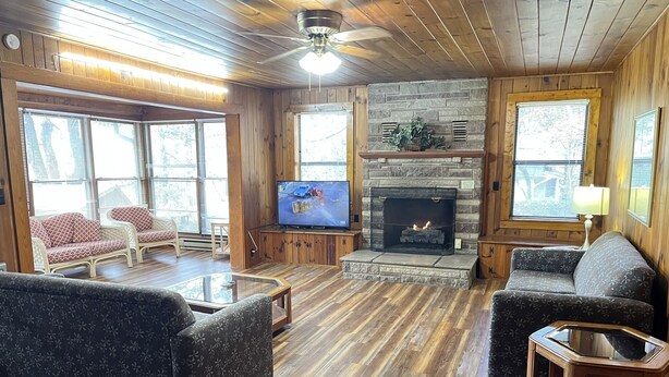 Una sala de estar acogedora con chimenea, piso de madera y televisor.