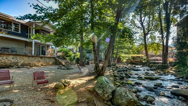 A courtyard with a stone wall, a small stream, and outdoor seating.