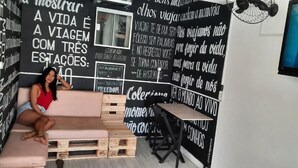 A room with a pink sofa, wooden crates, and a black and white patterned wall. - Soul do Mar Hostel (Cabo Frio)