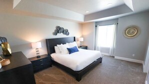 A modern bedroom with a large bed, bedside tables, a wall art piece, and a window with curtains.