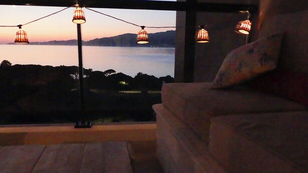 A room with a view of a body of water at dusk, a sofa, and hanging lamps. - A charming setting with the sea in full view! (Pietrosella)