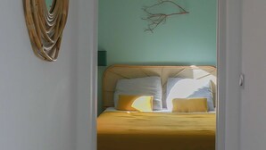A bedroom with a bed, a wall-mounted mirror, and a branch decoration. - A charming setting with the sea in full view! (Pietrosella)