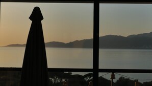 A room with a large window overlooking a body of water and distant hills. - A charming setting with the sea in full view! (Pietrosella)