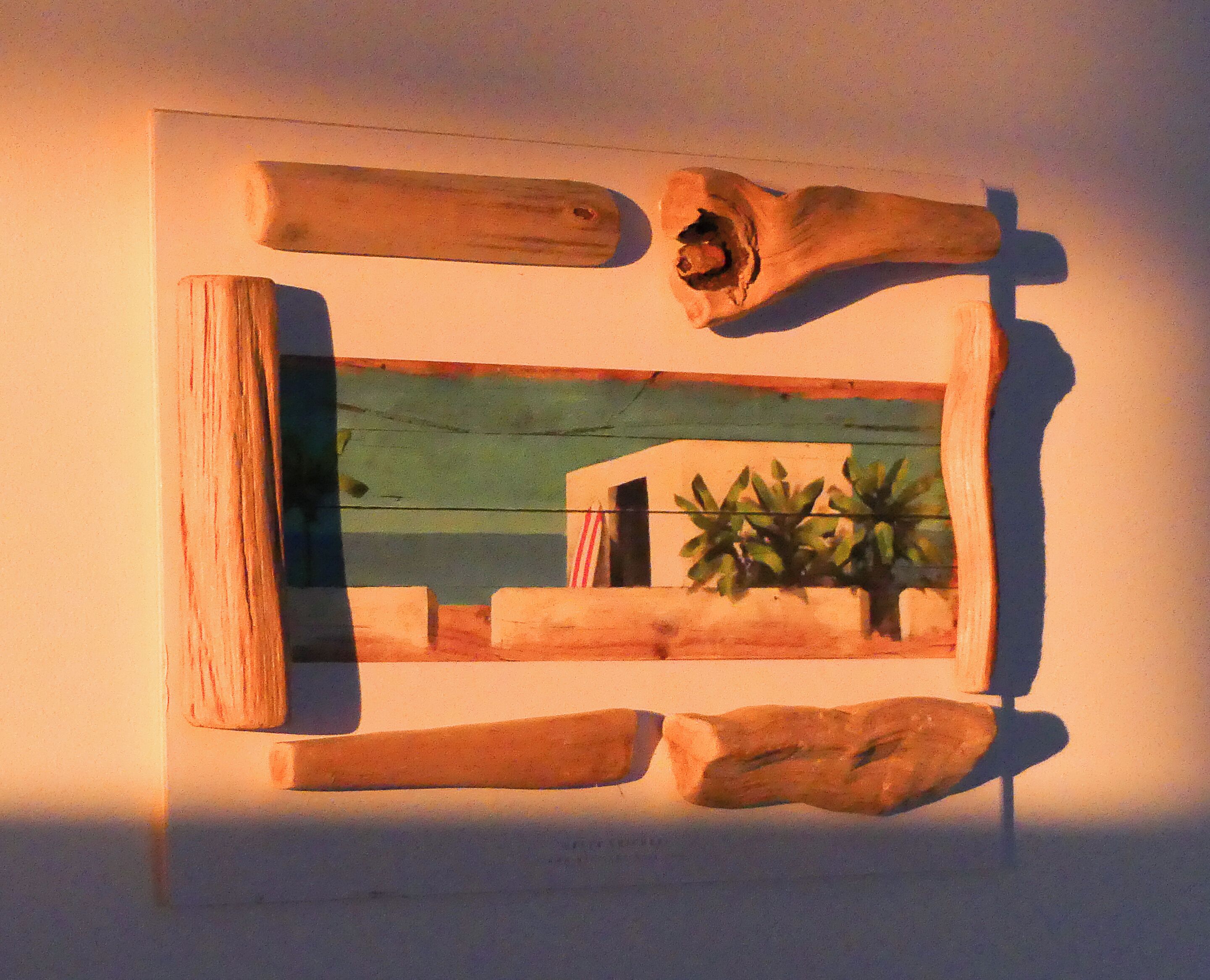 A framed artwork with a rustic, wooden texture and a small window-like opening.