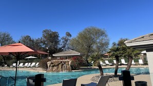 Cielo azzurro limpido, una piscina con lettini e una cascata.