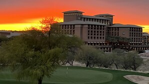 Un hotel con diversi piani e un tetto piatto, immerso in un campo da golf e alberi.