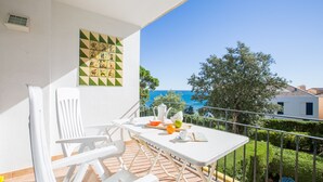 A balcony with a table set for breakfast, a view of the sea, and a decorative wall panel. - 1ROCM 1D - Apartment for 5 people with terrace just 150m from the beach of Calella de Palafrugell (Calella de Palafrugell)