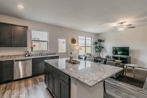 A modern kitchen with dark cabinetry, a granite countertop, and a central island.