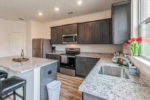 A modern kitchen with dark cabinets, granite countertops, stainless steel appliances, and a window with red tulips.