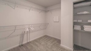 Uma lavanderia com varais de metal, uma porta branca e prateleiras com toalhas dobradas.