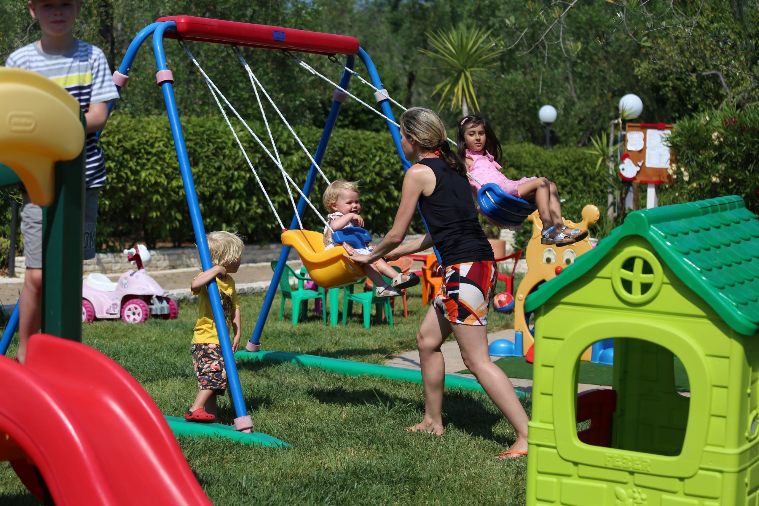 A playground with swings, slides, and a green playhouse.
