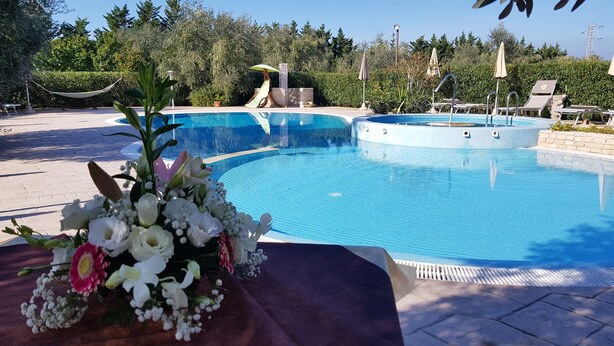 Une piscine entourée d’une terrasse, de chaises longues et agrémentée d’un arrangement floral.