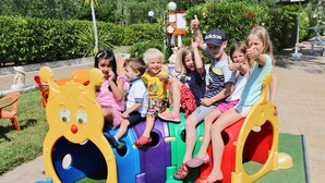 Des enfants jouent sur des jeux colorés dans un espace de jeux extérieur.