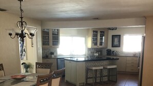 A spacious kitchen with a central island, a dining area with chairs, and a chandelier. - Cheerful 3 bedroom house with a heated pool (Naples)
