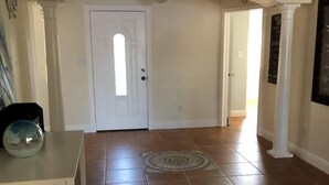 A spacious hallway with a white door, a small table with a decorative bowl, and a patterned rug on the floor. - Cheerful 3 bedroom house with a heated pool (Naples)