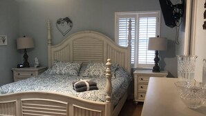 A bedroom with a bed, a nightstand, a dresser, a ceiling fan, and a window. - Cheerful 3 bedroom house with a heated pool (Naples)