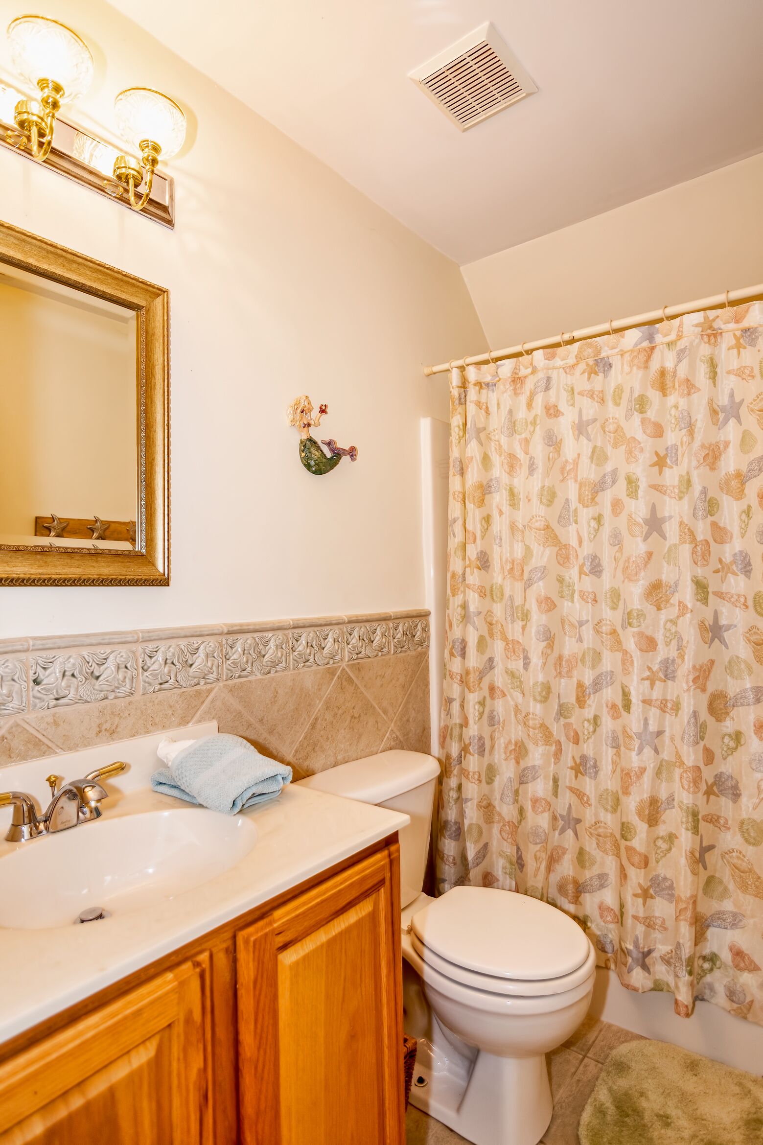 A bathroom with a white sink, a toilet, and a shower curtain with a sea-themed pattern.
