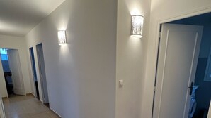 Ein Flur mit Holzboden, weißen Wänden und zwei Wandleuchten.