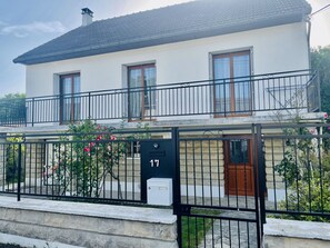 Une maison à deux étages avec un balcon, une boîte aux lettres et une plaque portant le numéro 17.