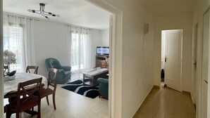 Ein geräumiger Wohnbereich mit Esstisch, Stühlen, einer Couch und einem Fernseher.