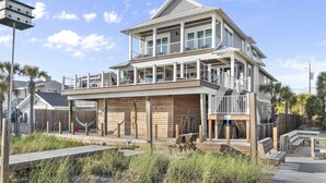 Une maison de deux étages située en bord de mer, dotée d’un balcon, d’une terrasse en bois et offrant une vue sur l’océan.