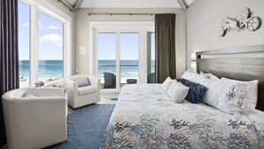 Une chambre dotée d’un grand lit, d’un coin salon et offrant une vue sur l’océan.