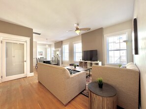 A spacious living area with a sofa set, a coffee table, and a TV. - ⌂ Elevated 2bed 1.5 Bath in a Historic 1913 Building ⌂ (Atlanta)
