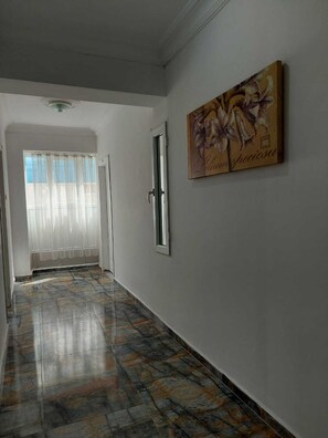 Ein Korridor mit einem gemusterten Boden, einer Tür und einem an der Wand hängenden Bild.
