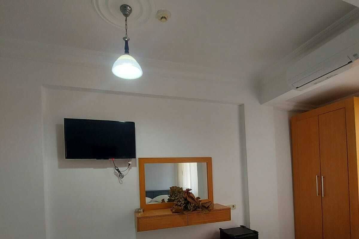 A hotel room with a bed, a TV, a mirror, a wardrobe, and a ceiling fan.