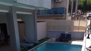 A swimming pool with lounge chairs and a covered area. - Pamukkale Hotel (Didim)