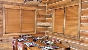Un interior de madera con una mesa de comedor, sillas y una lámpara colgante.