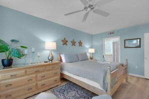 A bedroom with a bed, dresser, ceiling fan, and decorative starfish wall art. - Beach time! Destin West Condo Pelican 303 (Fort Walton Beach)