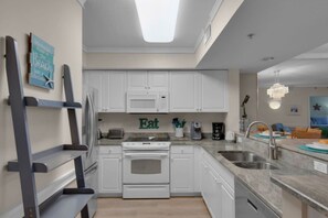 Una cocina moderna con armarios blancos, horno empotrado y encimera de granito.