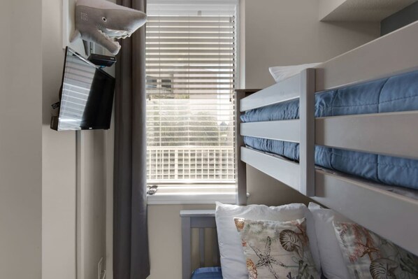Una habitación con literas, una ventana con persianas y un escritorio con ordenador.