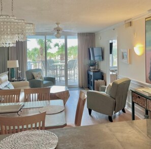 A spacious living area with a dining table, sofas, and a television. - Beach time! Destin West Condo Pelican 303 (Fort Walton Beach)